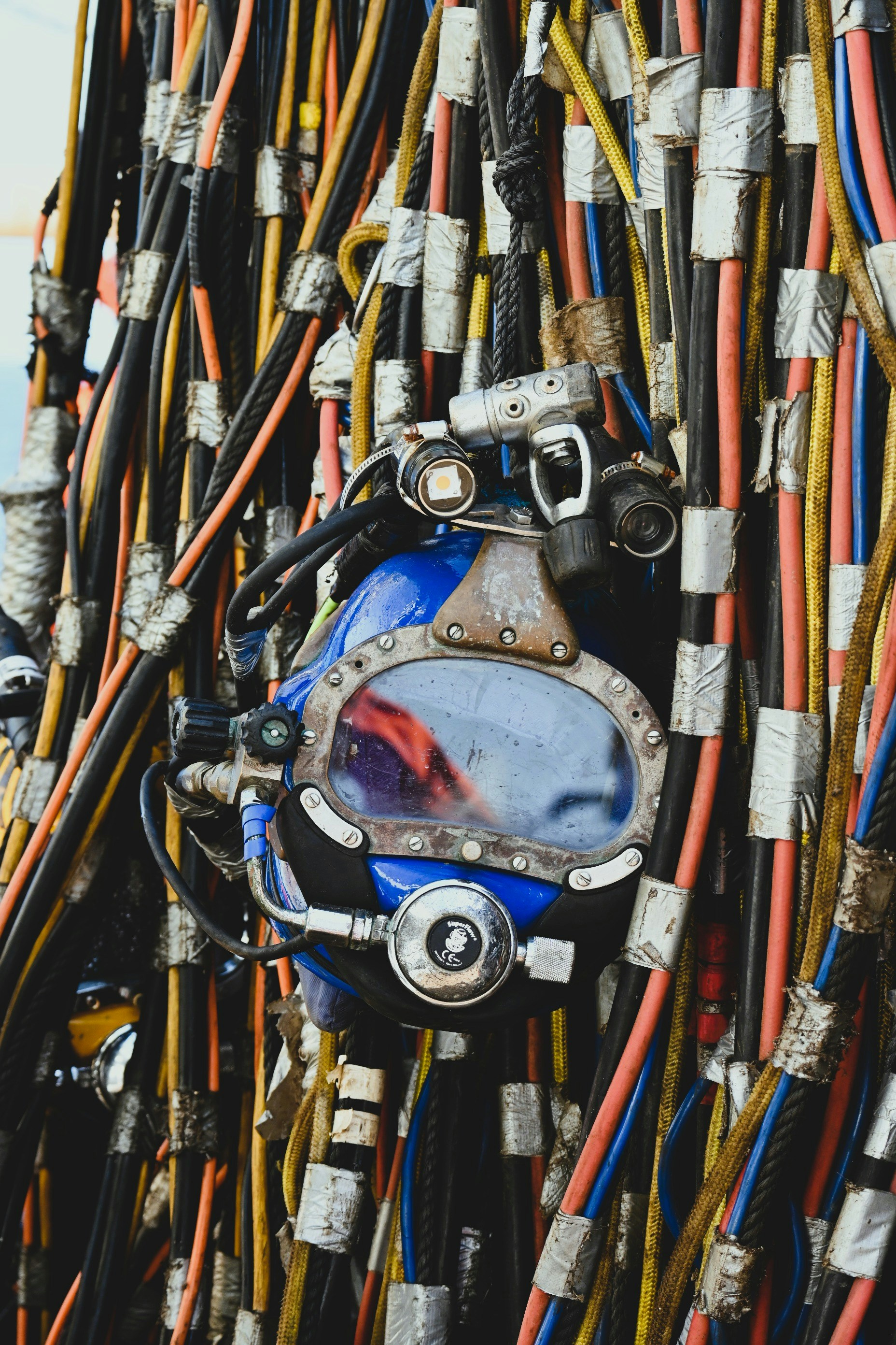 Commercial diving helmet among cables on an offshore deck.